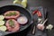 Beef steaks and cutting vegetables on grill pan on black slate background. Steak menu