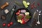 Beef steaks and cutting vegetables on grill pan, olive oil and spices on black slate background. Top view. Steak menu