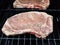 Beef steaks with seasoning cooking on barbecue grill