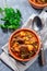 Beef stew with potato, green beans, carrot, peas and corn, in ceramic bowl, vertical, top view