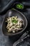Beef stroganoff with mushrooms in a plate with cremini and champignons. Black background. Top view