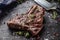 Beef T-Bone steak with salt pepper and rosemary on slate plate