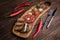 Beef Tartar with a raw egg yolk, rye bread and chilis on a wooden board with spoon and fork. Shot made from above on a dark rustic