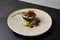 Beef tartare on rye bread with capers, cucumbers, cheese espuma and spices. Meat tartare on handmade ceramic plate. Innovative