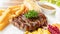 Beefsteak, French fries, and vegetable on a white plate