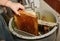 Beekeeper extracting fresh honey from a honeycomb with a knife tool and honey extractor