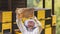 Beekeeper in front of beehive boxes, holding a frame with comb and bees