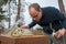 Beekeeper looks after his bee colony by lifting a plastic cover