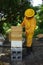A beekeeper placing a flow hive on top of a brooder box at an apiary in the tropics