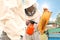 Beekeeper spraying sugar water onto hive frame at apiary. Harvesting honey