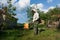 Beekeeper trimming tall grass in the apiary in protective clothes