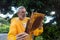 a beekeeper in the tropics examining a frame of brood at his apiary