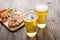 Beer being poured into glass with steak on wooden background