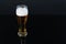 A beer bottle and a filled glass of beer. Black background with copyspace