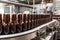 Beer bottling line with brown bottles on conveyor belts and bottling machine made of stainless steel.