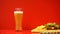 Beer with foam and hamburger on red background, carbohydrates and fatty foods