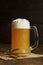 Beer with foam in a misted mug on a wooden background