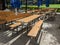 Beer garden with empty wet benches on the background of a green meadow