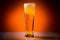 Beer glass with drops on a orange background. Alcohol concept. Copy space