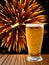 Beer glass on wooden table against of golden fireworks.