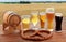 Beer glasses, barrel and pretzel over cereal field