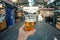 Beer in hand of visitor inside central food market of Copenhagen, Denmark. Many stores with drinks and delicacy food