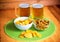 Beer mugs, potato chips and pretzels on wooden table