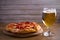 Beer and pepperoni pizza on wooden table. Glass of beer. Ale and food concept.