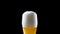 Beer is poured into the glass on a black background. Beer is poured into a glass. Glass with beer slow moving HD frames