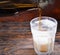 Beer is pouring into a frozen glass from brown bottle on dark wooden desk