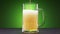 Beer slowly pours into a glass on green background