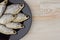 Beer snack: 6 sun-dried freshwater salt fish on black plate - a source of vitamins and protein, gray table, location right