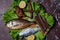 Beer snacks, dried and smoked fish, smoked neck, smoked quail, on a lettuce leaf, on a wooden plate.