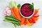 Beet hummus with fresh vegetables, above view on white marble