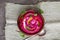 Beet puree with microgreens, olive oil and hemp seeds in a small wooden bowl.