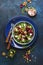 Beet summer salad with arugula, radicchio, soft cheese and walnuts on plate with fork, dressing and spices on blue kitchen table,