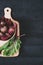 Beets with green tops in round metal pan on dark black wooden background, fresh red beetroot on backdrop kitchen table top view