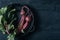 Beets with green tops in round metal pan on dark black wooden background, fresh red beetroot on backdrop kitchen table top view