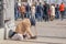 Beggar begging sitting on the ground near the Church and a crowd of people