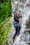 Beginner female climber on top rope, climbing a sport route near Sinaia town, in Bucegi mountains, Romania, on a chilly Spring day