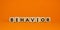 Behavior symbol. Wooden cubes with word `behavior`. Beautiful orange background. Business, psychology and behavior concept. Copy