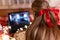 Behind female head with long blondie hair and red bow rear view watching the christmas movie on laptop at camping home in cozy bed