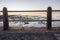 Behind a hand rail on the beachfront promenade at sunset