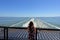 A behind view of a young woman riding a BC ferry at the back, looking over the railing at the vast blue ocean of georgia strait