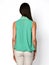 From behind. Young beautiful woman posing in blue mint shirt and beige gray pants on a white