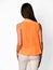 From behind. Young beautiful woman posing in orange shirt and beige pants on a white