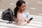 Behind of young black woman smiling with mobile phone