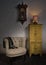Beige armchair, yellow cupboard, pendulum clock and illuminated table lamp