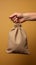 Beige background, a hand holds subsidy themed canvas bag, assistance concept