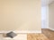 Beige blank wall empty interior with pillows, carpet, curtain and herringbone wood floor.